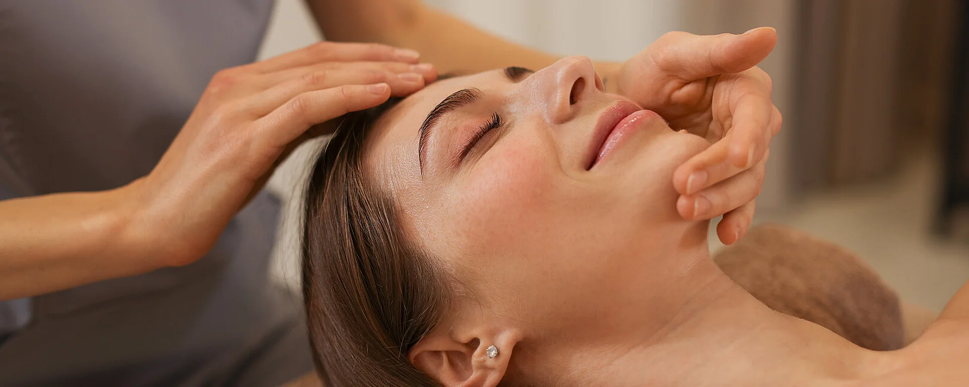 Beautiful woman receiving facial massage indoors, closeup